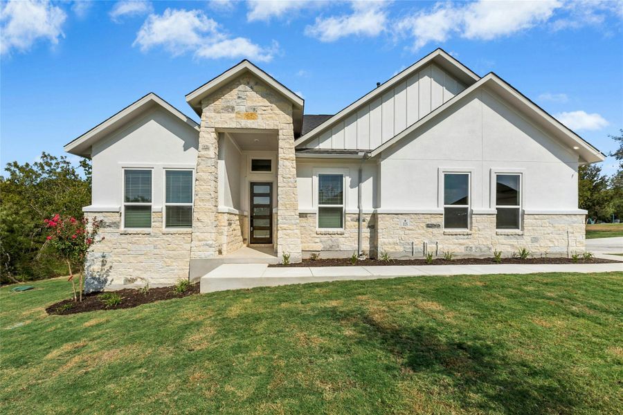 View of front of home with stone siding, a front yard, and board and batten siding View of front of home with stone siding, a front yard, and board and batten siding