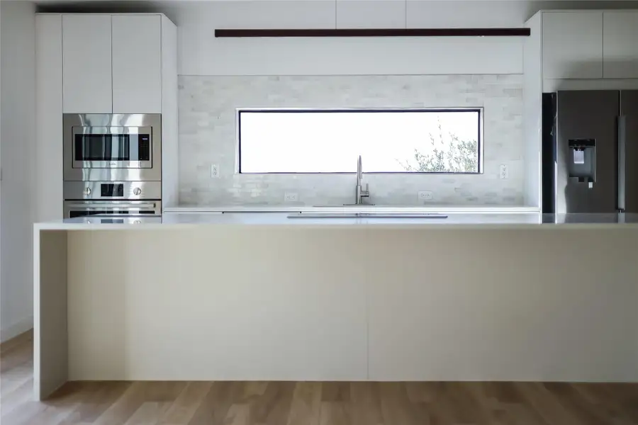 Kitchen featuring appliances with stainless steel finishes, modern cabinets, white cabinetry, and decorative backsplash Kitchen featuring appliances with stainless steel finishes, modern cabinets, white cabinetry, and decorative backsplash