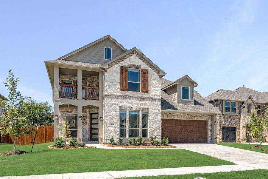 Two-story home with stone and brick exterior, second-floor balcony, wood shutters, and two-car garage Two-story home with stone and brick exterior, second-floor balcony, wood shutters, and two-car garage