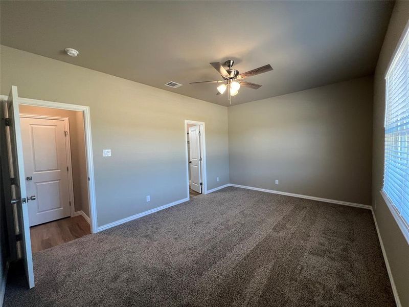 Unfurnished bedroom with dark carpet and ceiling fan