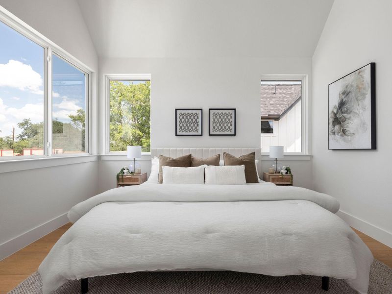 A tranquil primary bedroom with vaulted ceilings and abundant natural light.
