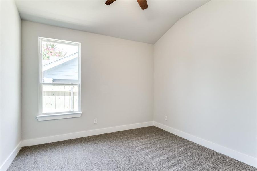 Carpeted empty room with plenty of natural light, ceiling fan, and lofted ceiling