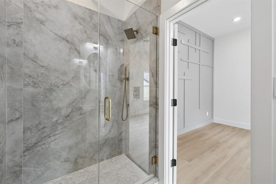 Full bath featuring a marble finish shower and wood finished floors