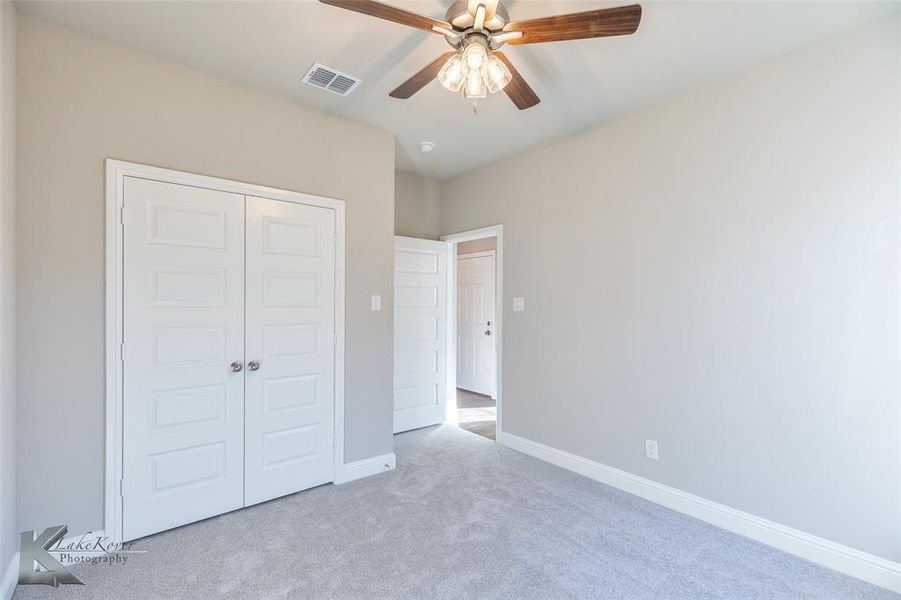Unfurnished bedroom with carpet, ceiling fan, and a closet