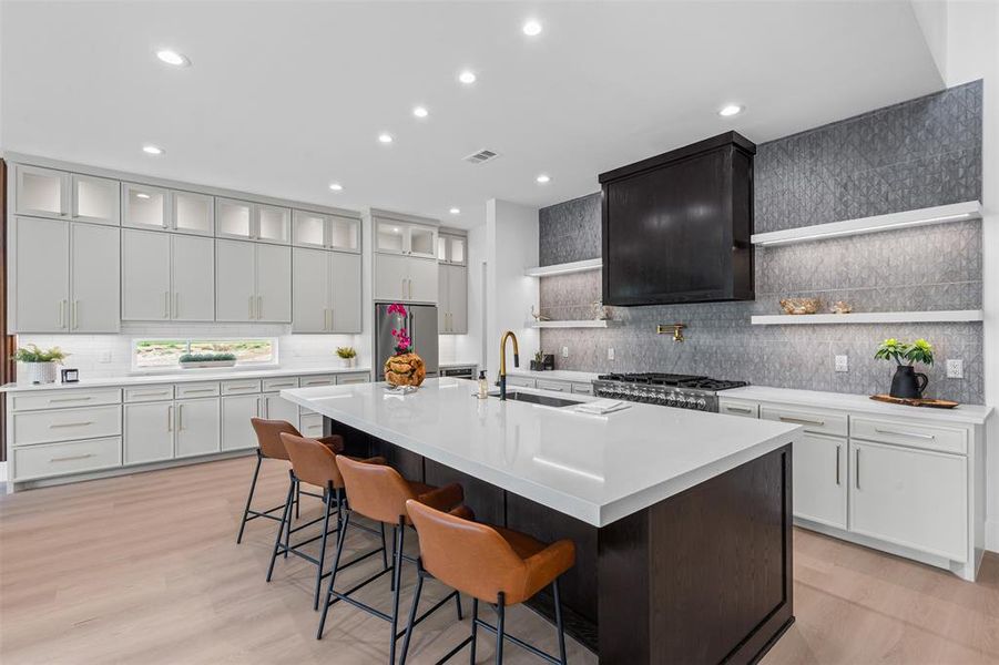 Kitchen with a breakfast bar, tasteful backsplash, a large island, light wood-style flooring, and open shelves