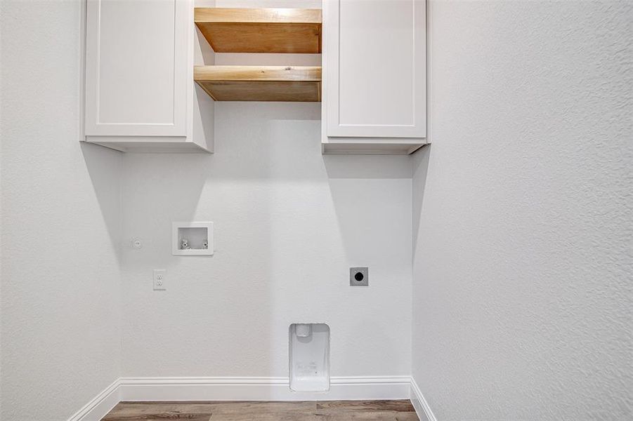 Clothes washing area with hookup for an electric dryer, washer hookup, cabinets, gas dryer hookup, and hardwood / wood-style flooring