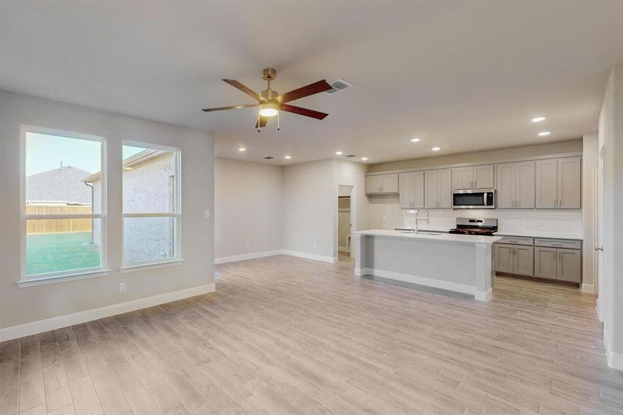 Kitchen with appliances with stainless steel finishes, gray cabinets, light hardwood / wood-style flooring, and sink