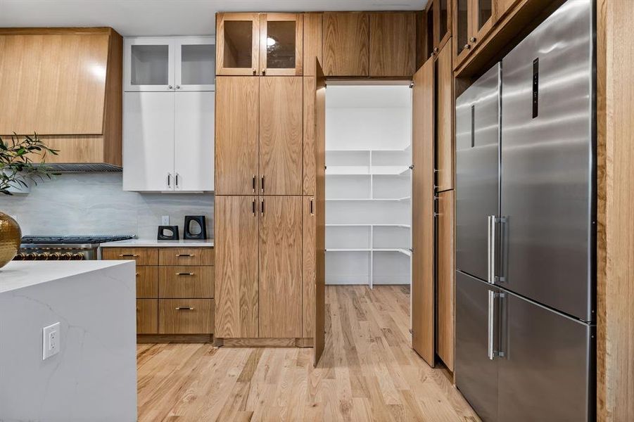 Kitchen featuring white cabinetry, backsplash, built in fridge, and light hardwood / wood-style flooring