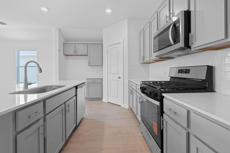 Kitchen with gray cabinetry, appliances with stainless steel finishes, recessed lighting, backsplash, and light wood-style flooring Kitchen with gray cabinetry, appliances with stainless steel finishes, recessed lighting, backsplash, and light wood-style flooring