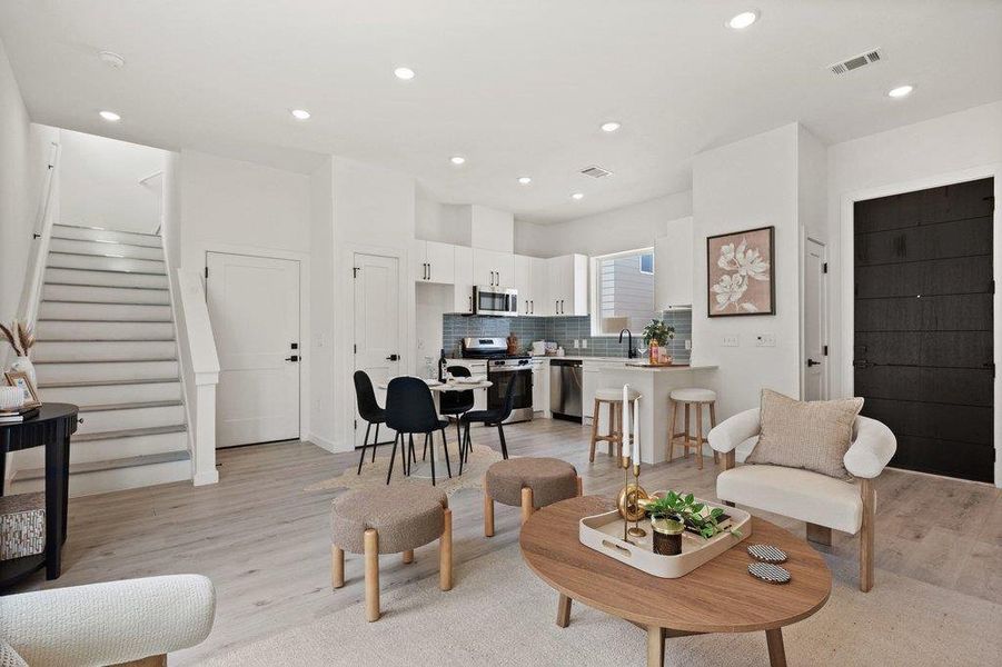 The property features an open concept living area with light-toned flooring, recessed lighting, and a prominent dark-paneled door