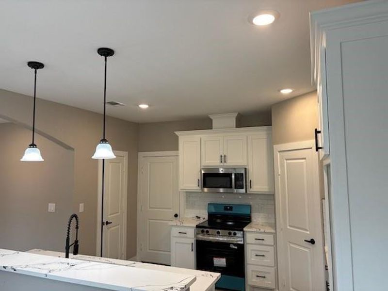 Kitchen featuring stainless steel appliances, tasteful backsplash, pendant lighting, white cabinets, and recessed lighting Kitchen featuring stainless steel appliances, tasteful backsplash, pendant lighting, white cabinets, and recessed lighting