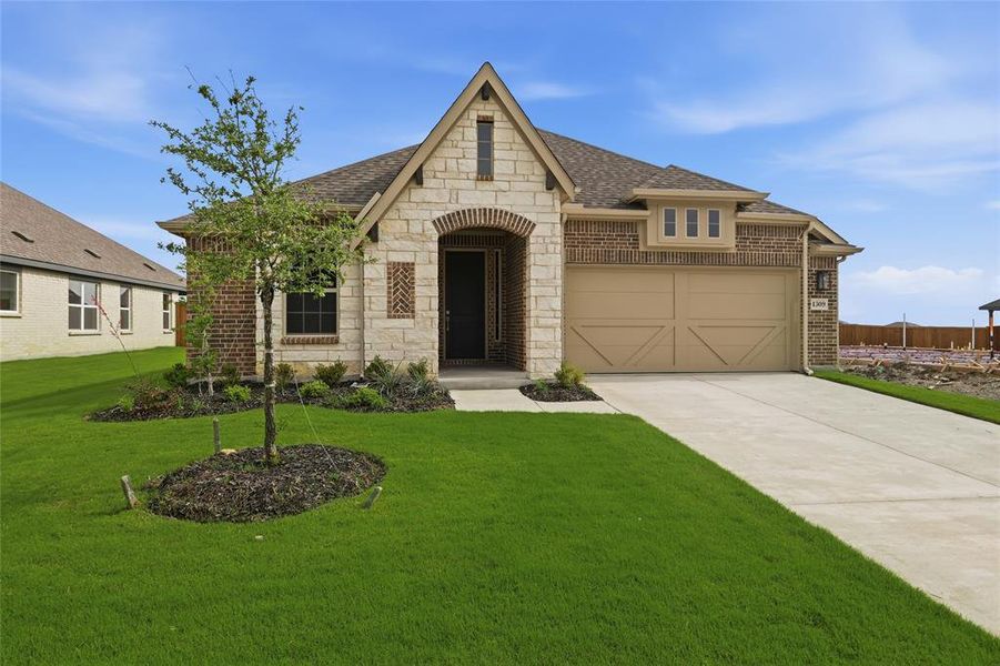 Brick and stone exterior featuring an arched entry, a two-car garage, a concrete driveway, and a front lawn with landscaping Brick and stone exterior featuring an arched entry, a two-car garage, a concrete driveway, and a front lawn with landscaping
