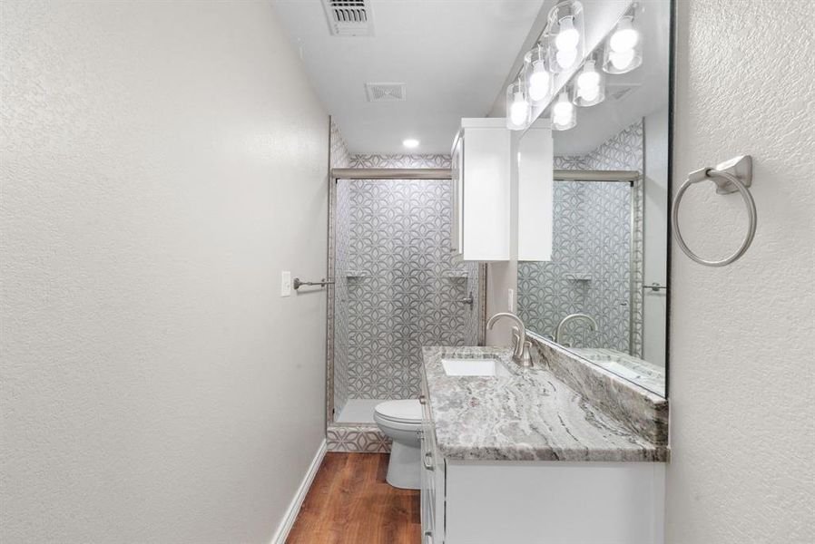 Bathroom featuring wood-type flooring, vanity, and a shower with shower door Bathroom featuring wood-type flooring, vanity, and a shower with shower door