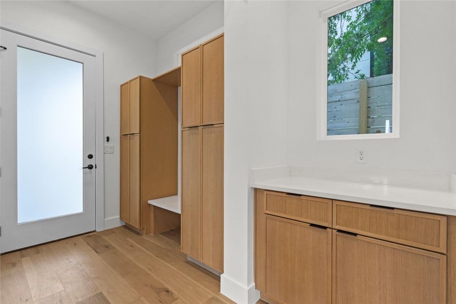 Hardwood flooring extends throughout this functional utility space with built-in cabinetry and a bright window.