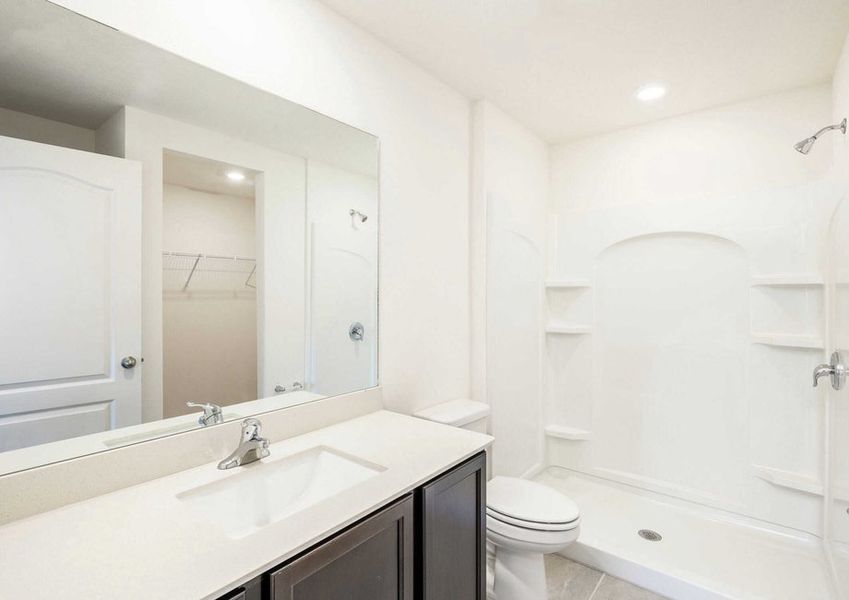 TheÂ Caladesi floor plan's master bathroom with quartzÂ countertops, dark brown cabinets and a walk-in shower.