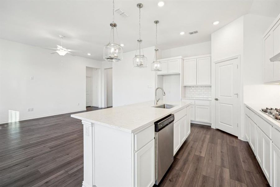 Kitchen with white cabinets, ceiling fan, dishwasher, and a center island with sink