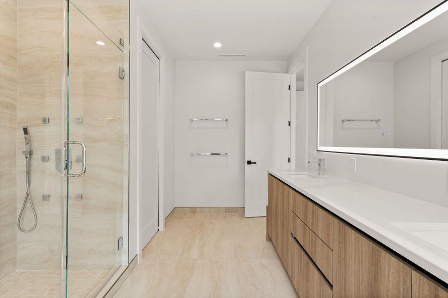 Smooth stone tiling and clean wood cabinetry define this modern bath with glass-enclosed shower.