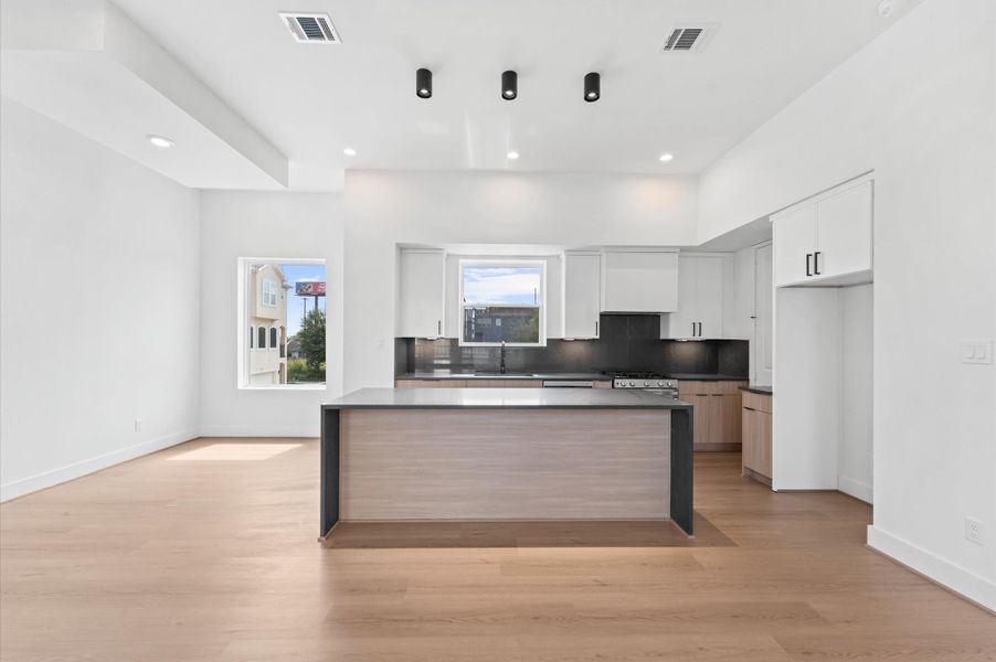 Chef's kitchen featuring dark grey 3CM luxury quartz waterfall island and euro white oak cabinetry Chef's kitchen featuring dark grey 3CM luxury quartz waterfall island and euro white oak cabinetry