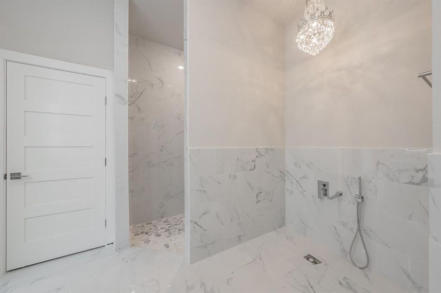 Full bathroom featuring a marble finish shower, a chandelier, marble finish flooring, and tile walls