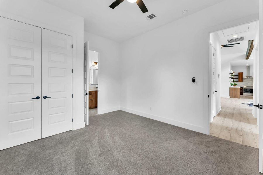 Unfurnished bedroom featuring attic access, light colored carpet, a closet, and ensuite bath