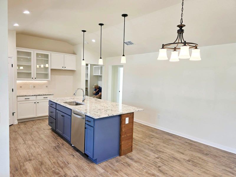Kitchen featuring glass insert cabinets, white cabinetry, decorative light fixtures, backsplash, and lofted ceiling