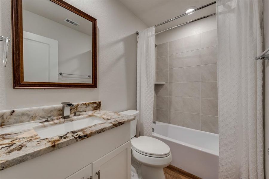 Ensuite Full bathroom featuring exotic granite vanity with framed mirror, hardwood floors, and shower / bath combo with shower.