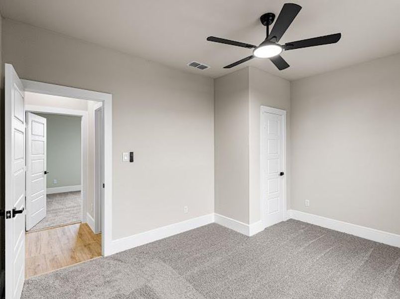 Empty room featuring light colored carpet and ceiling fan Empty room featuring light colored carpet and ceiling fan