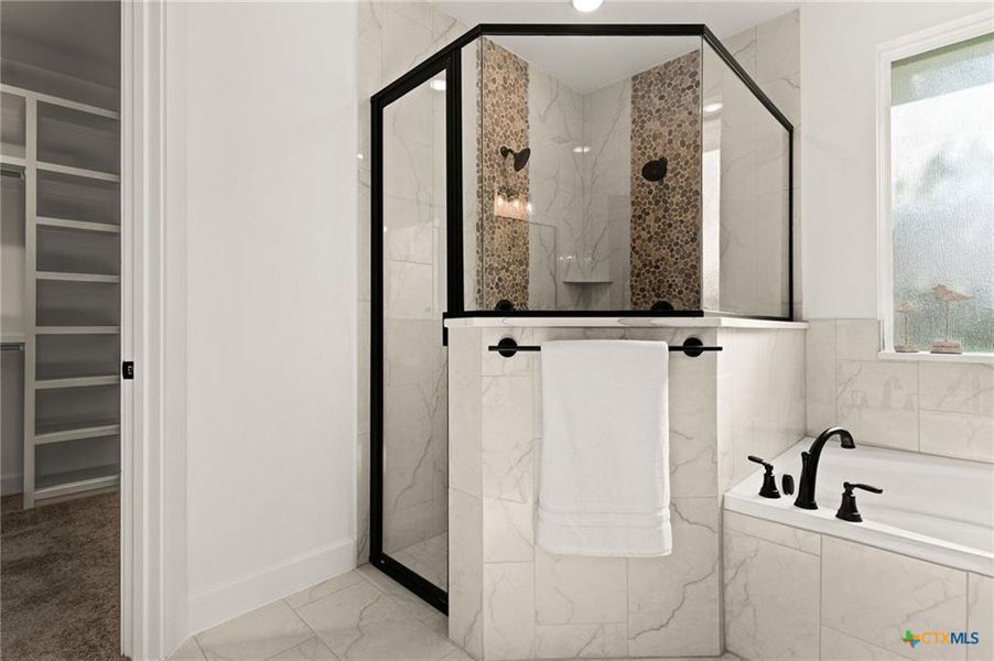 Bathroom featuring a spacious closet, a marble finish shower, healthy amount of natural light, and a garden tub