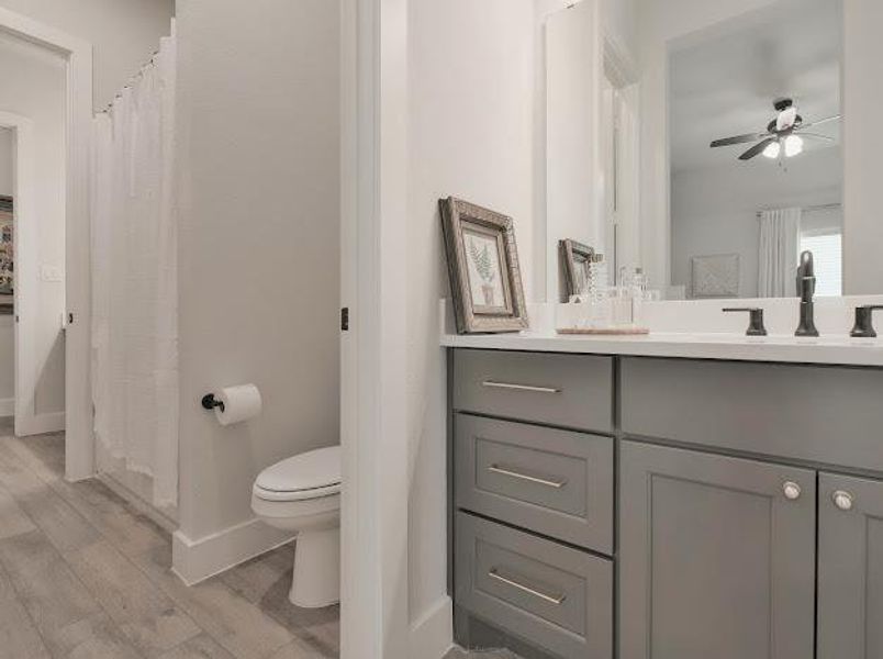 Full bathroom with vanity, light wood finished floors, ceiling fan, and curtained shower Full bathroom with vanity, light wood finished floors, ceiling fan, and curtained shower