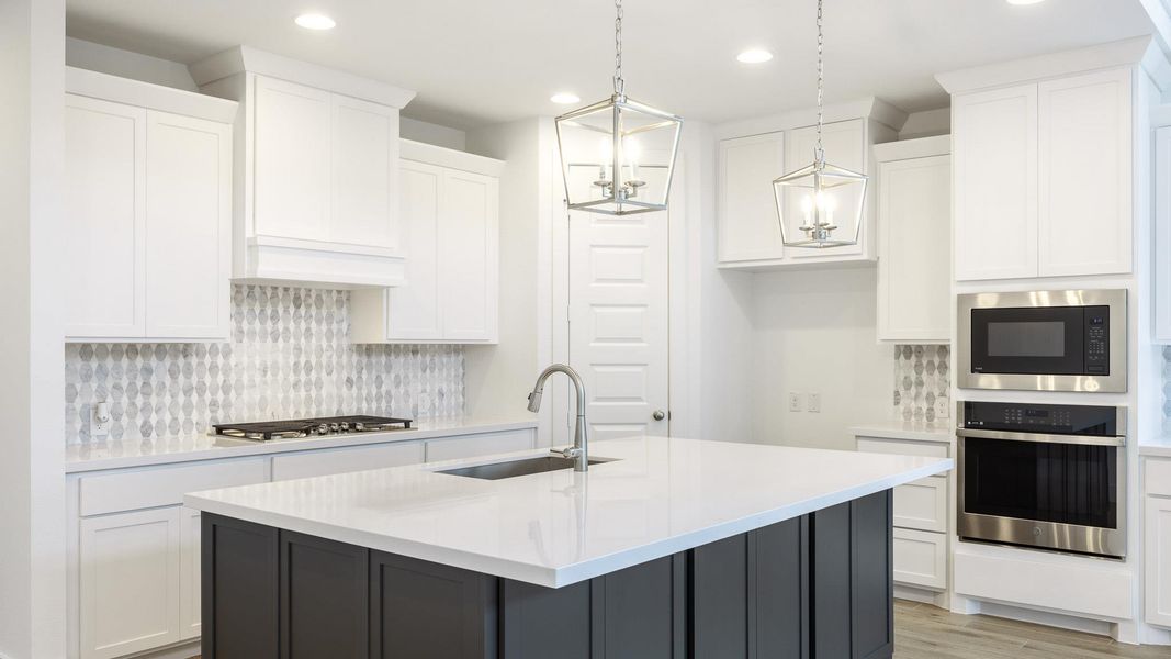 Kitchen featuring appliances with stainless steel finishes, a sink, recessed lighting, white cabinets, and light countertops Kitchen featuring appliances with stainless steel finishes, a sink, recessed lighting, white cabinets, and light countertops