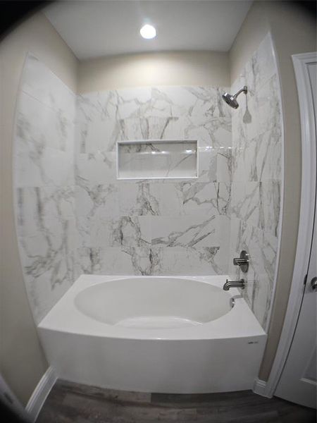 Bathroom with hardwood / wood-style flooring and tiled shower / bath combo