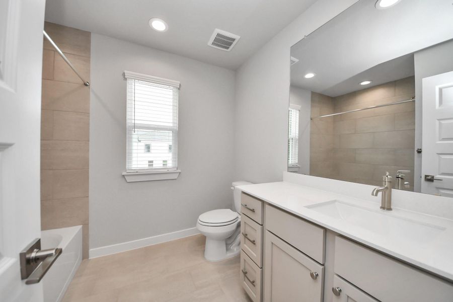 Secondary bath features tile flooring, walk-in shower with tile surround, light stained wood cabinets, beautiful light countertop. Secondary bath features tile flooring, walk-in shower with tile surround, light stained wood cabinets, beautiful light countertop.