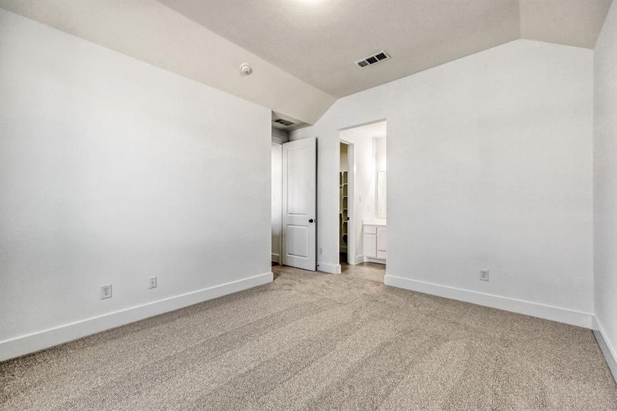 Unfurnished bedroom with light colored carpet and connected bathroom