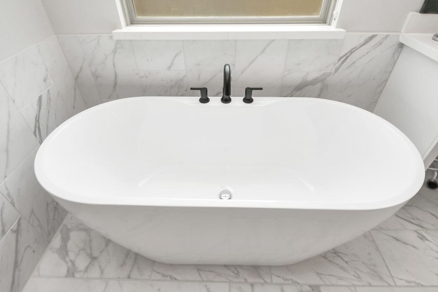 Modern freestanding soaking tub with matte-black fixtures.