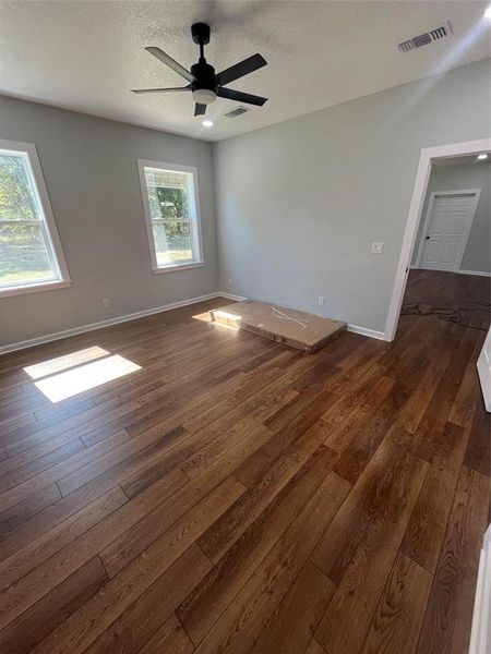 Unfurnished room with a textured ceiling, dark wood-style flooring, and ceiling fan Unfurnished room with a textured ceiling, dark wood-style flooring, and ceiling fan