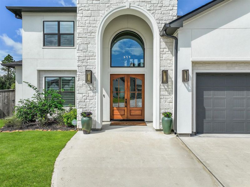 Double wood & glass entry doors are tucked beneath a dramatic two-story arched entry, complemented by an oversized arched window that fills the soaring foyer with natural light.