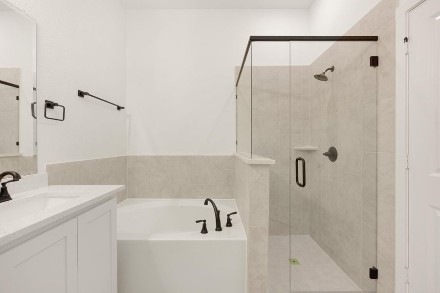 Bathroom with soaking tub, glass walk-in shower, tile walls, and white vanity with dark bronze fixtures Bathroom with soaking tub, glass walk-in shower, tile walls, and white vanity with dark bronze fixtures