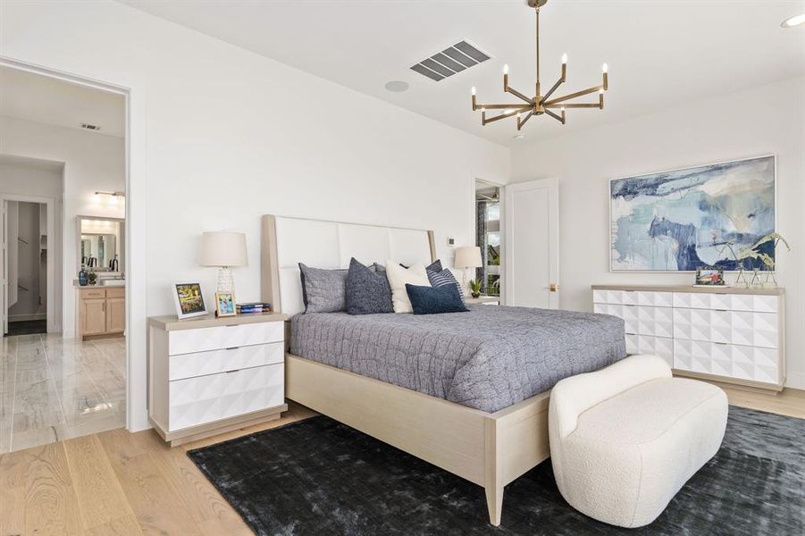 Bedroom featuring light wood finished floors and a chandelier Bedroom featuring light wood finished floors and a chandelier