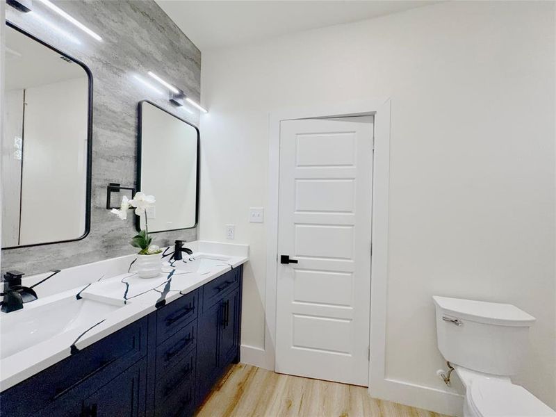 Double vanity featuring dark cabinetry, white countertops with black veining, and dual rectangular mirrors with black frames