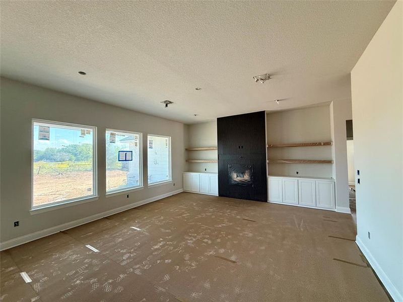 Unfurnished living room featuring baseboards and a textured ceiling Unfurnished living room featuring baseboards and a textured ceiling