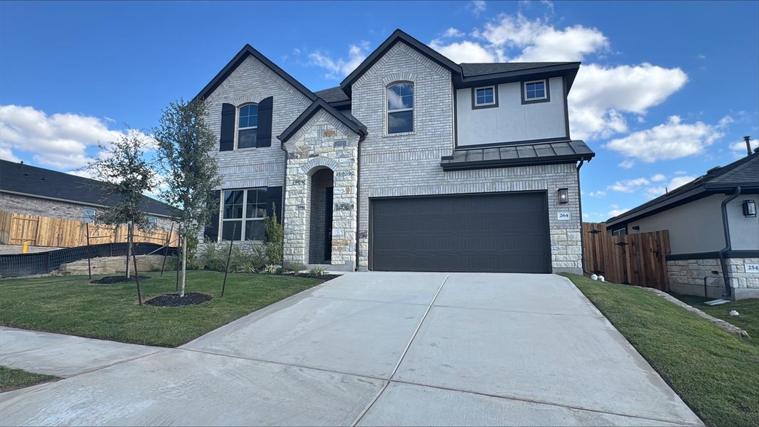 French country home with stone siding, driveway, an attached garage, and brick siding French country home with stone siding, driveway, an attached garage, and brick siding
