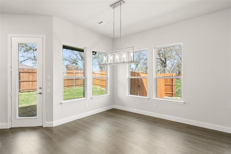 Unfurnished dining area with dark wood-style flooring, baseboards, and plenty of natural light