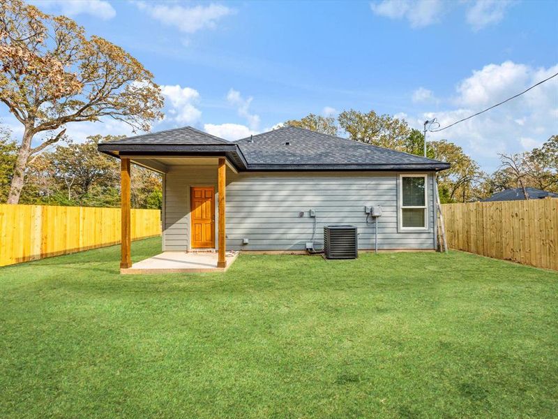 Rear view of house featuring a fenced backyard, a patio, and a shingled roof