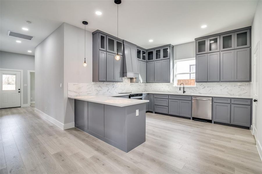 Kitchen with kitchen peninsula, dishwasher, hanging light fixtures, and plenty of natural light