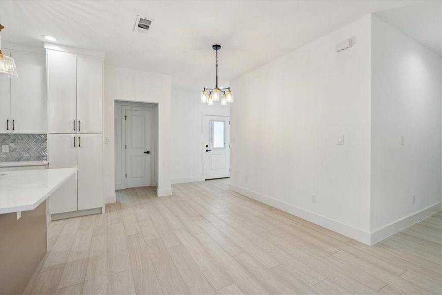 Kitchen with light hardwood / wood-style flooring, a notable chandelier, decorative light fixtures, and white cabinetry