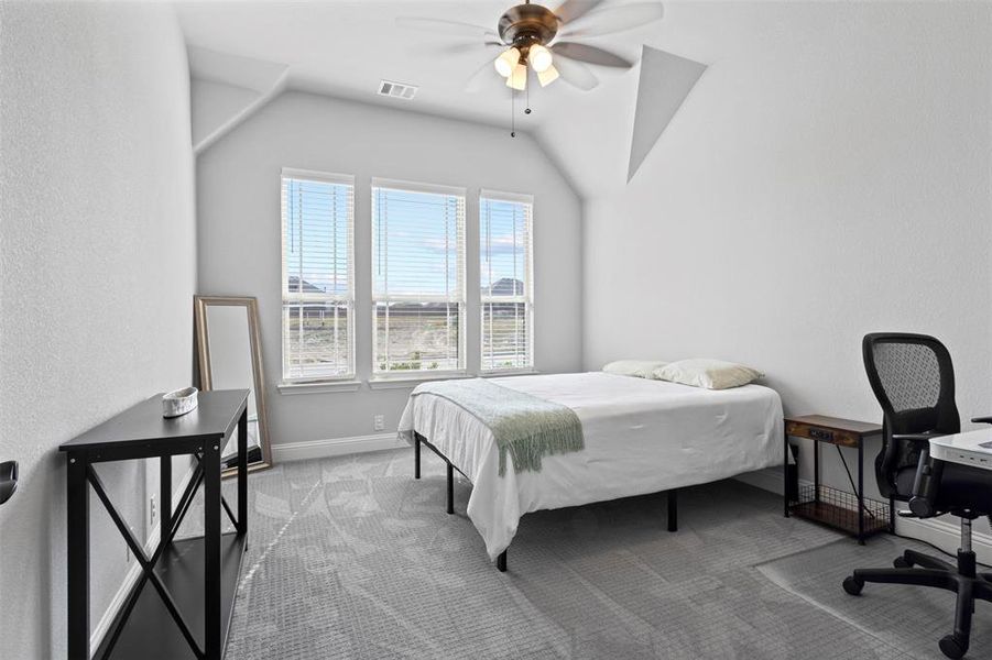 Bedroom with ceiling fan, carpet floors, and lofted ceiling