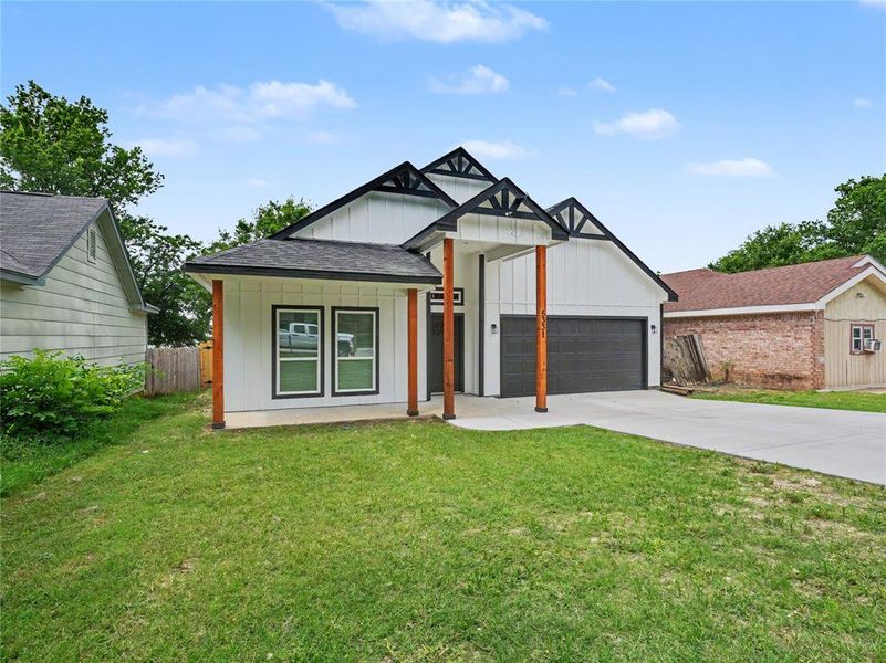 Modern farmhouse exterior featuring white board-and-batten siding, a dark gray garage door, and black-trimmed gables Modern farmhouse exterior featuring white board-and-batten siding, a dark gray garage door, and black-trimmed gables