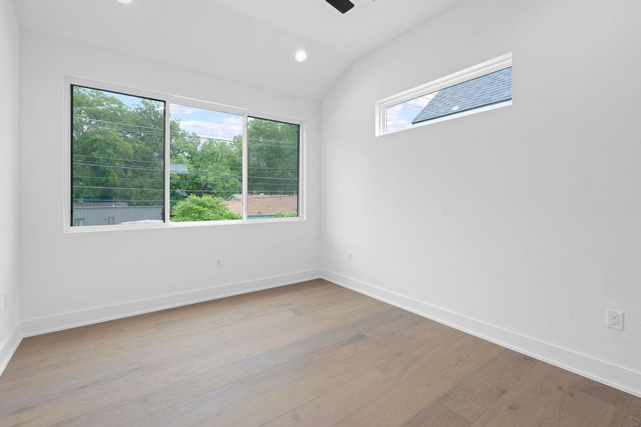 Spare room with plenty of natural light, light wood-style floors, vaulted ceiling, and recessed lighting