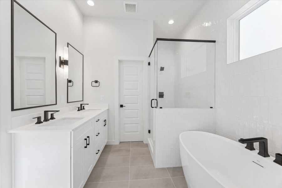 View from the primary closet into the bathroom highlights the dual sinks and spacious layout, emphasizing the functional and luxurious design of the primary suite.