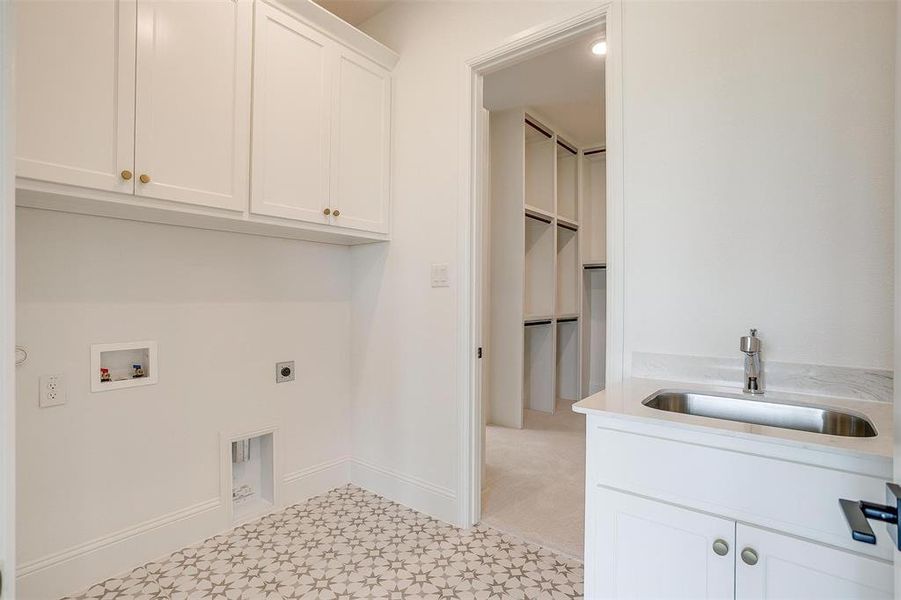 Washroom with cabinets, electric dryer hookup, light carpet, washer hookup, and sink